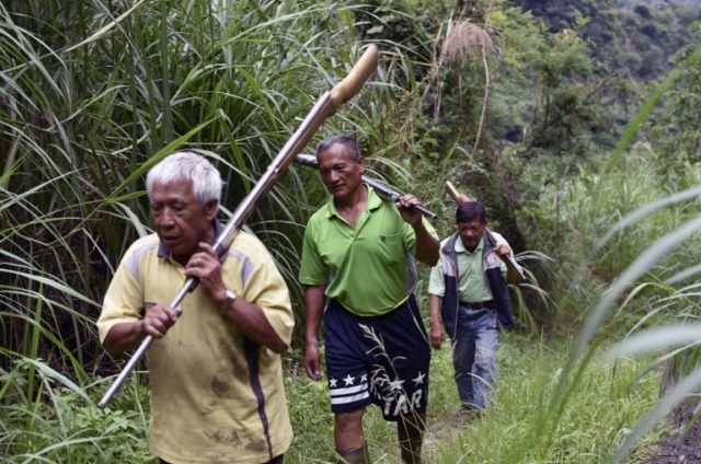 Tama Talum (C) and fellow aboriginal hunters, carry shotguns in the mountains in Taitung,