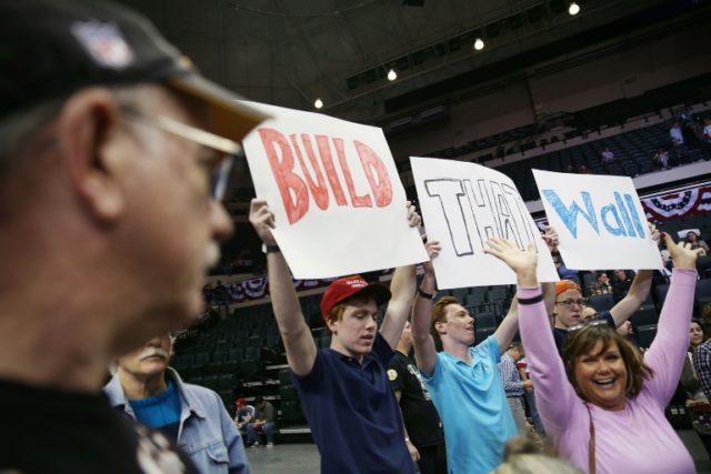 People hold signs that read, "Build that Wall", as they wait for the start of a campaign r