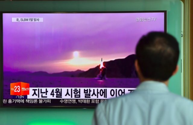 A passer-by watches a TV broadcast at a railway station in Seoul on July 9, 2016, showing