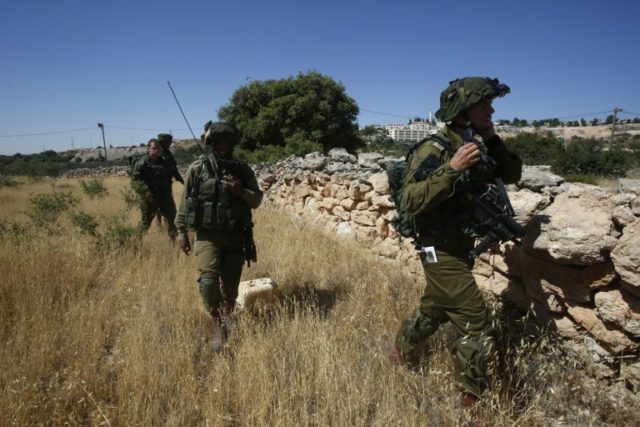 Israeli soldiers inspect the area around the Jewish settlement of Kiryat Arba where a 13-y