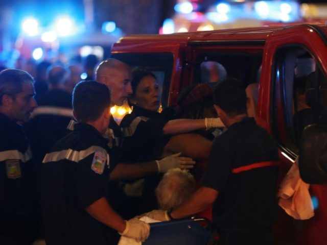 Rescue workers help injured people to get in a ambulance on July 15, 2016, after a truck d