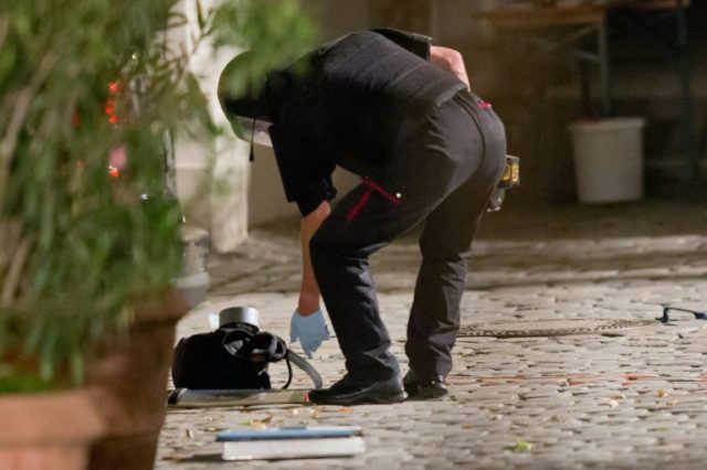 A policeman in protective gear inspects a backpack used to carry an explosive device at th