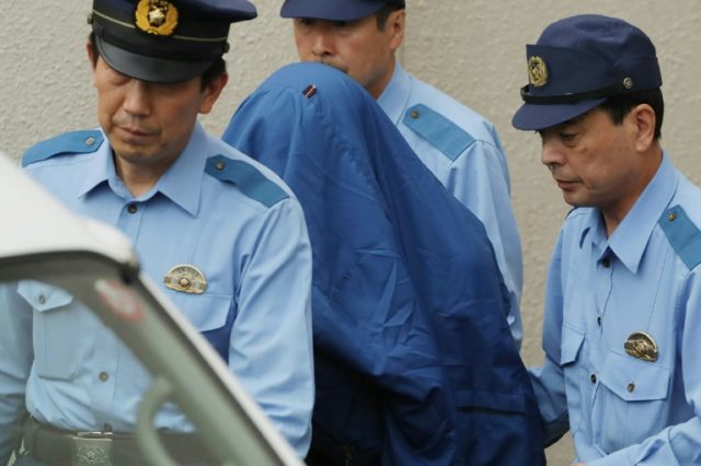 Murder suspect Satoshi Uematsu (C, in blue shroud) is escorted to a van heading to the pro