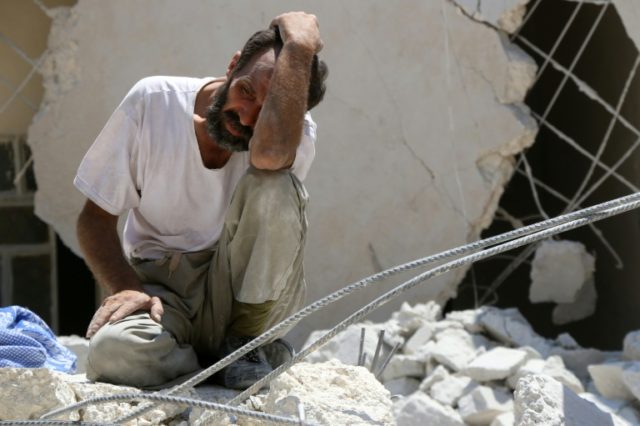 A man pictured in the rubble of a collapsed building following reported air strikes in Ale