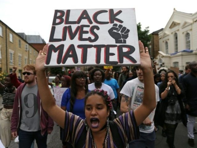 A women holds up a placard with the slogan "Black Lives Matter" as people march in Brixton, south London to protest against police brutality in the US after two recent incidents where black men have been shot and killed by police officers