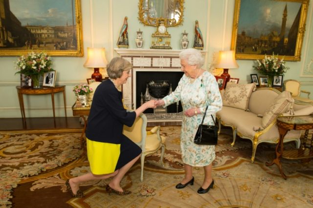 The new leader of the Conservative Party Theresa May (L) kneels as she is greeted by Brita