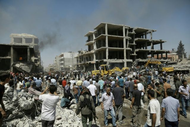 People gather at the site of a bomb attack in the northeastern Syrian city of Qamishli on