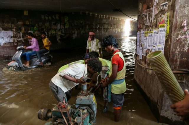 Indian municipal cooperation workers set up a motor to pump water from a flooded subway in