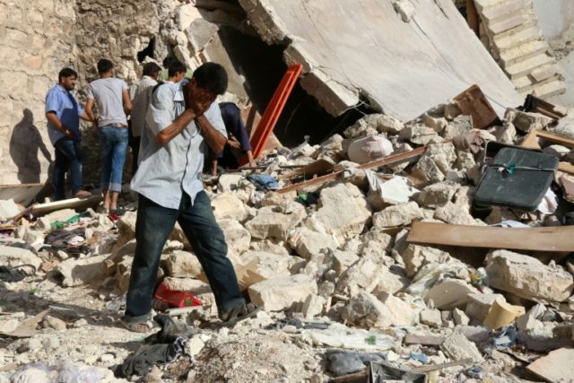 A Syrian man reacts as rescuers look for victims under the rubble of a collapsed building