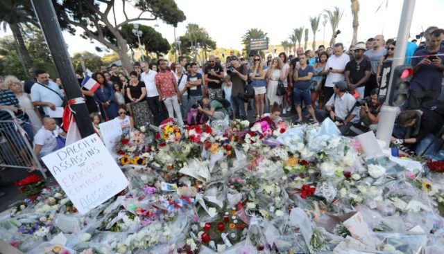 People gather around a makeshift memorial to pay tribute to the victims of an attack in th
