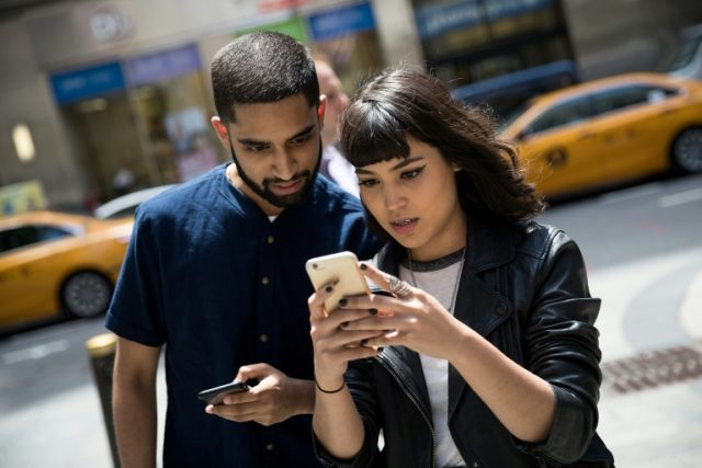 Sameer Uddin and Michelle Macias play Pokemon Go on their smartphones, outside Nintendo's