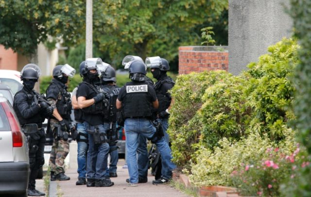 French policemen stand in a street during the search of a house in the Normandy village of