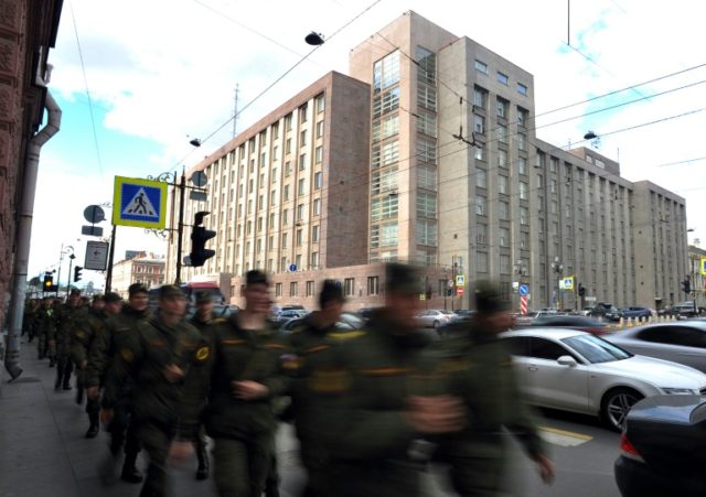 Russian soldiers walk past the local headquarters of the FSB, formerly the KGB, in central