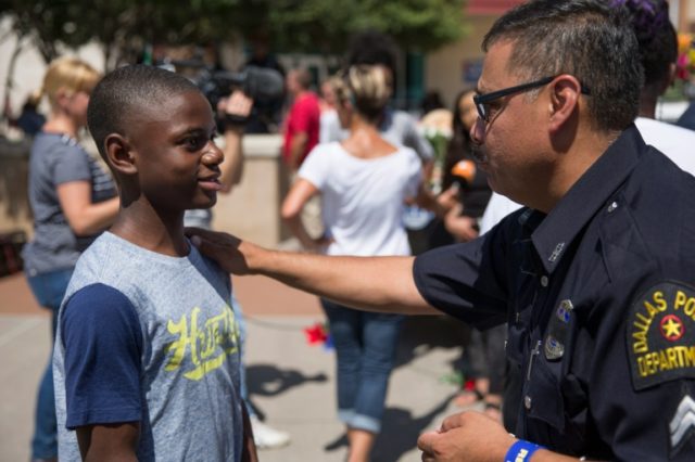 A police officer talks with a boy at a memorial outside Dallas Police Headquarters