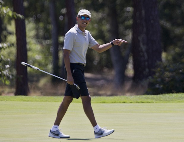 President Barack Obama reacts after putting on the first green as he plays golf at Farm Ne