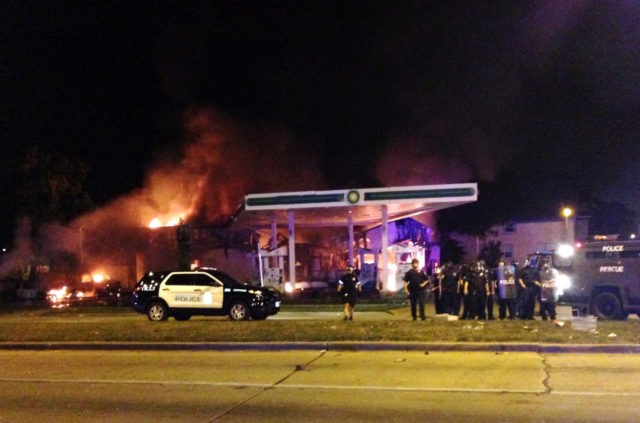 Authorities respond near a burning gas station as dozens of people protest following the f