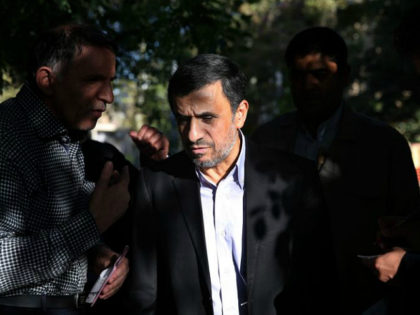 Former Iranian President Mahmoud Ahmadinejad, center, talks with a man after receiving his