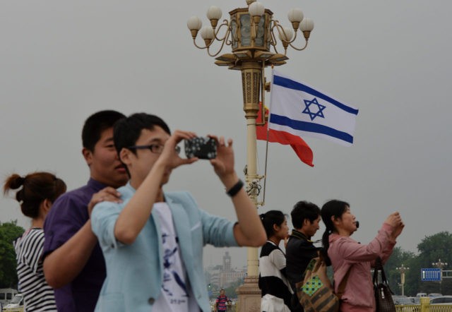 Chinese tourists watch the motorcade of Israeli Prime Minister Benjamin Netanyahu as he ar