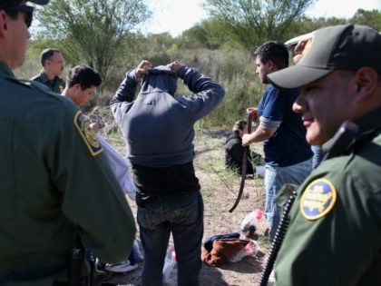 Undocumented immigrants remove items of clothing while being searched by U.S. Border Patro