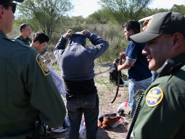 Undocumented immigrants remove items of clothing while being searched by U.S. Border Patrol agents who caught them on December 7, 2015 near Rio Grande City, Texas.