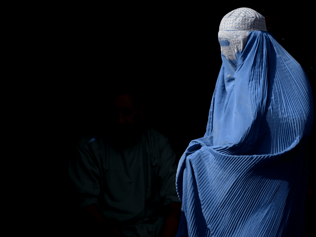 TOPSHOT - A burqa-clad Afghan woman walks along a road in Herat on July 28, 2016. / AFP / AREF KARIMI (Photo credit should read AREF KARIMI/AFP/Getty Images)