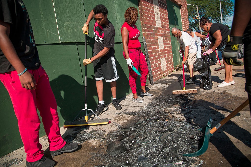 MILWAUKEE, WI - AUGUST 14: Community members and volunteers help clean up the damage to a few local business after rioters clashed with the Milwaukee Police Department protesting an officer involved killing August 14, 2016 in Milwaukee, Wisconsin. Hundreds of angry people confronted police after an officer shot and killed a fleeing armed man earlier in the day. (Photo by Darren Hauck/Getty Images)