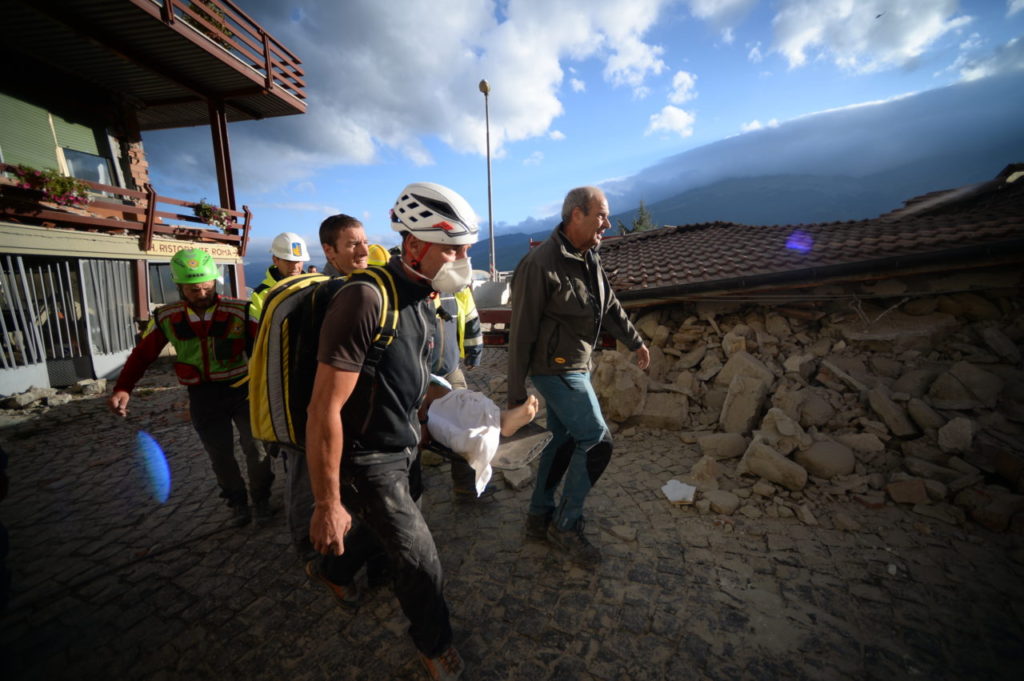 Rescuers carry an injured man among damaged homes after a strong heathquake hit Amatrice on August 24, 2016. Central Italy was struck by a powerful, 6.2-magnitude earthquake in the early hours, which has killed at least three people and devastated dozens of mountain villages. Numerous buildings had collapsed in communities close to the epicenter of the quake near the town of Norcia in the region of Umbria, witnesses told Italian media, with an increase in the death toll highly likely. / AFP / FILIPPO MONTEFORTE (Photo credit should read FILIPPO MONTEFORTE/AFP/Getty Images)