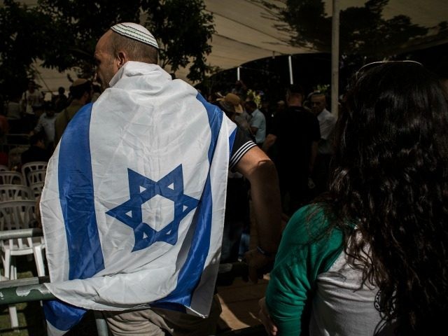 A man wears an Israeli flag during the funeral for Israeli Lt. Hadar Goldin on August 3, 2014 in Kfar-saba, Israel. Goldin was thought to have been captured during fighting in Gaza, but was later declared killed in action by the Israeli Defence Force (IDF). (Photo by Ilia Yefimovich/Getty Images)