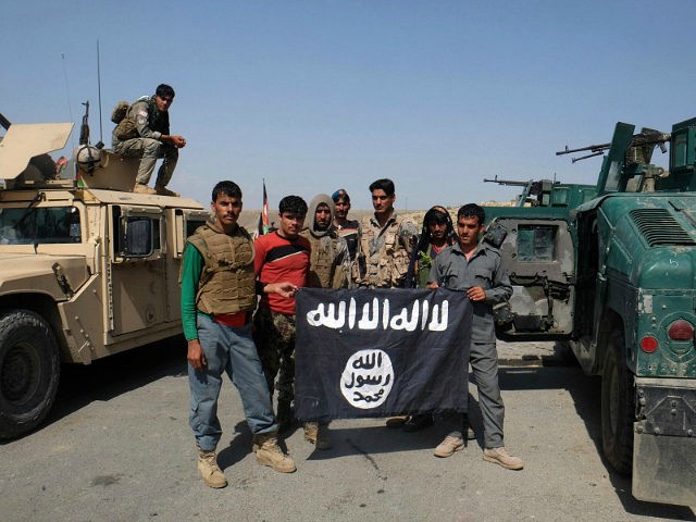 Afghan police poses for photograph with an Islamic State flag after an operation in the Ko