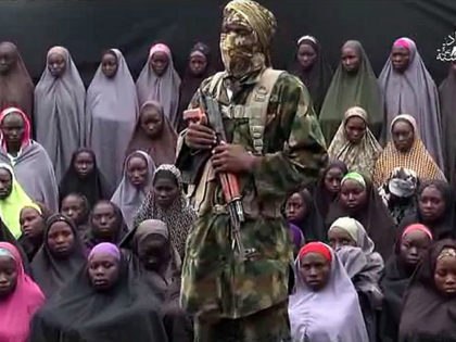 TOPSHOT - This video grab image created on August 14, 2016 taken from a video released on youtube purportedly by Islamist group Boko Haram showing what is claimed to be one of the groups fighters at an undisclosed location standing in front of girls allegedly kidnapped from Chibok in April …