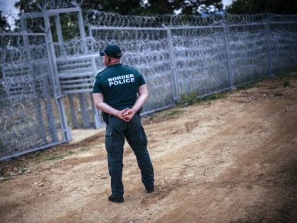 A border policeman stands next to a barbed wire wall on the Bulgarian border with Turkey, near the village of Golyam Dervent on July 17, 2014. Overwhelmed by an influx of mostly Syrian immigrants, Bulgaria has taken steps to secure its EU border -- including building a barbed-wire fence -- …