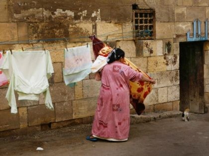 CAIRO, EGYPT - FEBRUARY 26: An Egyptian woman collects her washing which was hung out to dry on the outer wall of the Mamluk 15th century madrasa of Sultan Qaytbay, where an Arabic sign proclaims "Allah" over a low doorway, on February 26, 2009 in Cairo, Egypt. Despite being known …