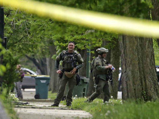 Chicago SWAT officers gather outside a house after rushing the structure where a man suspe