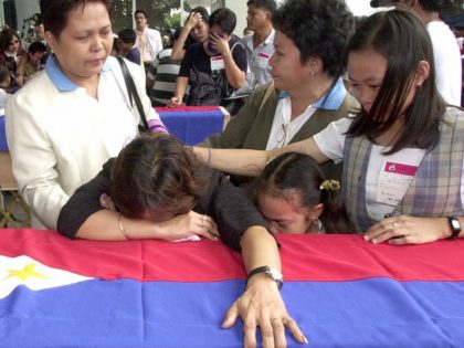 Miriam Templo and her daughters weeps over the flag-draped coffin bearing the remains of G