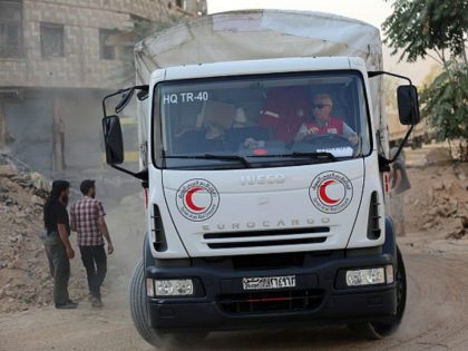 A member of the Syrian Arab Red Crescent (SARC) drives a truck as a convoy of SARC and United Nations' vehicles arrives in the rebel-held area of Harasta on the northeastern outskirts of the capital Damascus on August 29, 2016. / AFP / AMER ALMOHIBANY (Photo credit should read AMER …