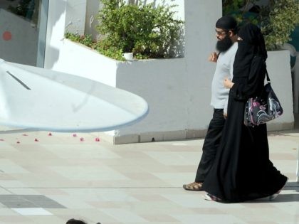 A woman wearing a niqab walks alongside her husband at the pool of a hotel in the Tunisian coastal holiday city of Mahdia, on August 29, 2012. According to some local media, fewer women go to the beach wearing bikinis as they fear attacks by religious extremists after the Islamist …