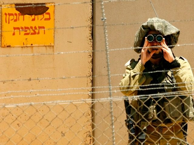 An Israeli soldier looks through his binoculars as he monitors the southern Lebanese village of Kfar Kila from the Israeli town of Metula, as seen from the Lebanese side of the border, on May 11, 2012. The Israeli military is building a wall that will run several kilometres (miles) along …