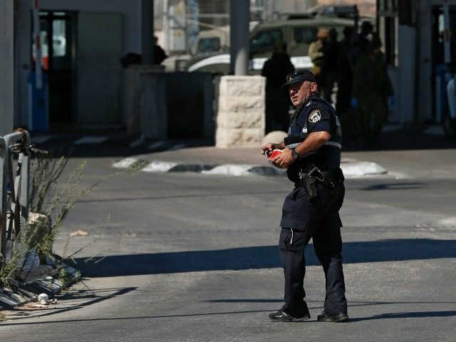An Israeli policeman walks as security forces guard the area on July 26, 2016 at the Qalandia crossing between the West Bank city of Ramallah and Israeli-annexed east Jerusalem, after Israeli private security guards shot and wounded an 18-year-old Palestinian suspected of planning to stab them. A police statement said …