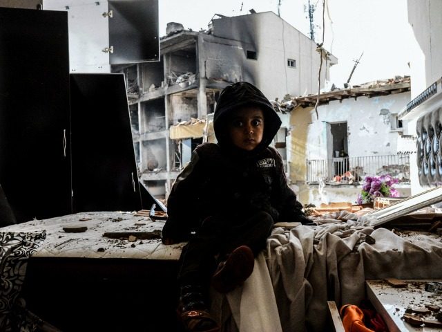 A child sits in front of the wreckage of a blast damaged building on January 14, 2016 in D