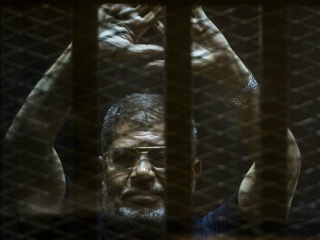 Ousted Egyptian president Mohamed Morsi gestures from the defendants cage as he attends hi