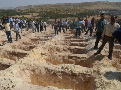 People wait close to empty graves at a cemetery during the funeral for the victims of last night's attack on a wedding party that left 50 dead in Gaziantep in southeastern Turkey near the Syrian border on August 21, 2016. At least 50 people were killed when a suspected suicide …