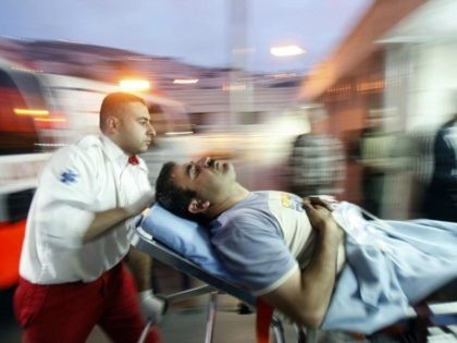 A Palestinian paramedic wheels a wounded man into the emergency ward of a hospital in the