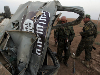 IRAQ, Mosul : Peshmerga fighters inspect the remains of a car, bearing an image of the trademark jihadist flag, which belonged to Islamic State (IS) militants after it was targeted by an American air strike in the village of Baqufa, north of Mosul, on August 18,2014. Kurdish peshmerga fighters backed …