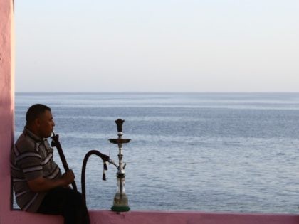 Two men sit on wall overlooking the Red Sea at a popular cafe in the northwestern Saudi town of al-Wajh on April 25, 2016.
