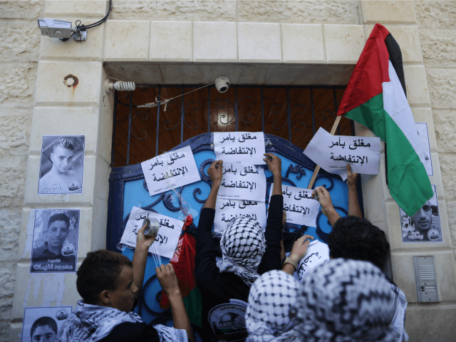 Masked Palestinian youths place slogans near pictures of Palestinians who died during viol