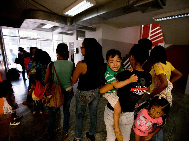 In this Feb. 11, 2016 photo, a child cries as he held by his mother who waits in line to s