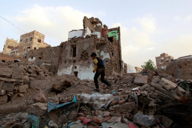 A Yemeni boy running past buildings that were damaged by air strikes carried out by the Sa