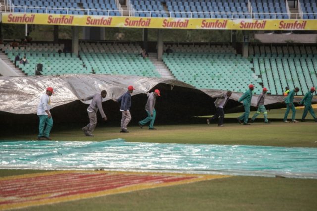 Workers pull a cover onto the pitch as rain delays start of play on the second day of the