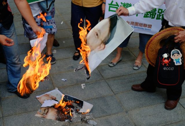 Activists burn the portrait of visiting Sha Hailin, a standing committee member of the Com