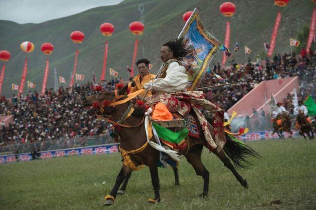 Ethnic Tibetans in traditional dress show off their skills in the saddle at a local govern